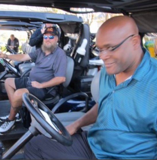 Two golfers riding in a golf cart at the tournament