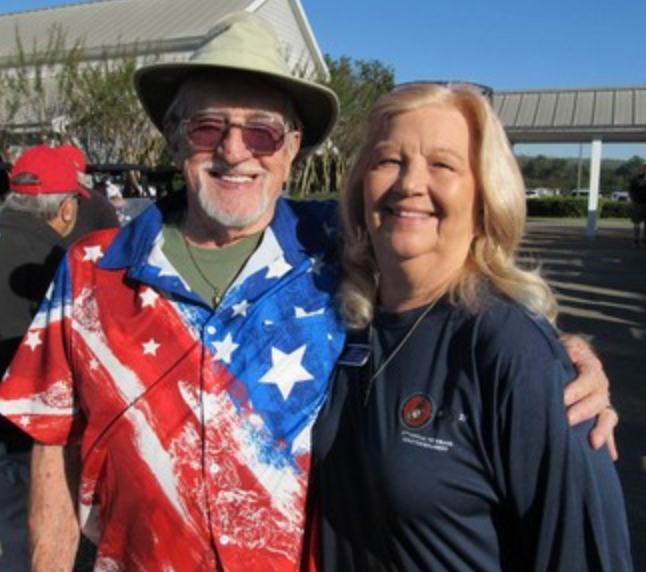 Man in American flag shirt and woman in Marine Corps shirt smiling together