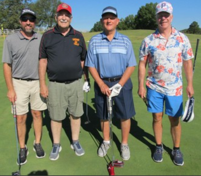 Foursome posing on the course, one in a floral shirt