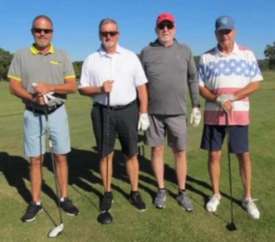 Foursome posing on the course in red and blue caps