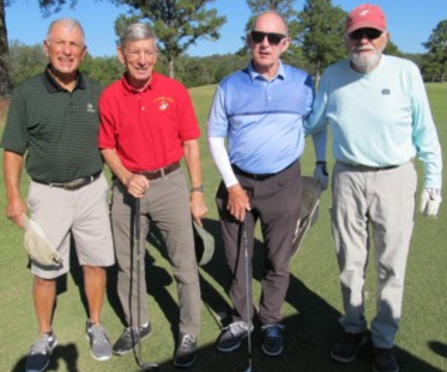 Foursome posing on the course, one in a red Marines shirt