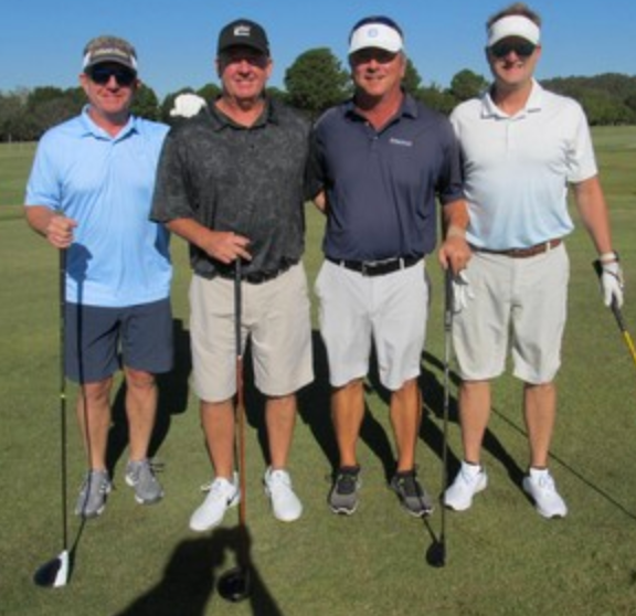 Foursome posing on the course wearing visors