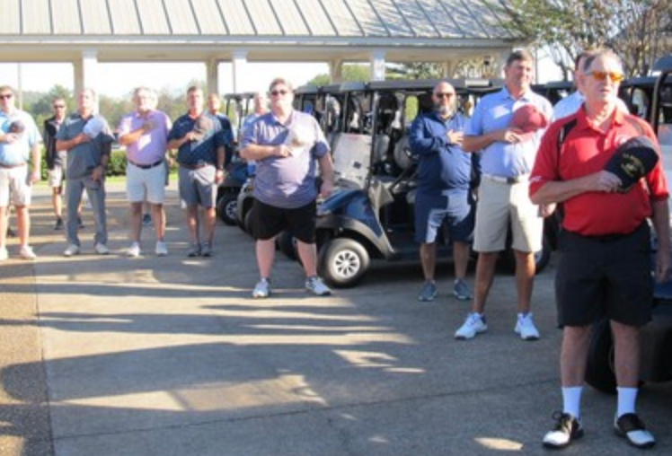 Golfers standing at attention with golf carts