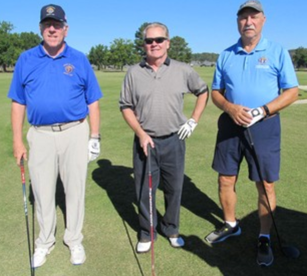 Three golfers posing on the fairway, two in blue caps