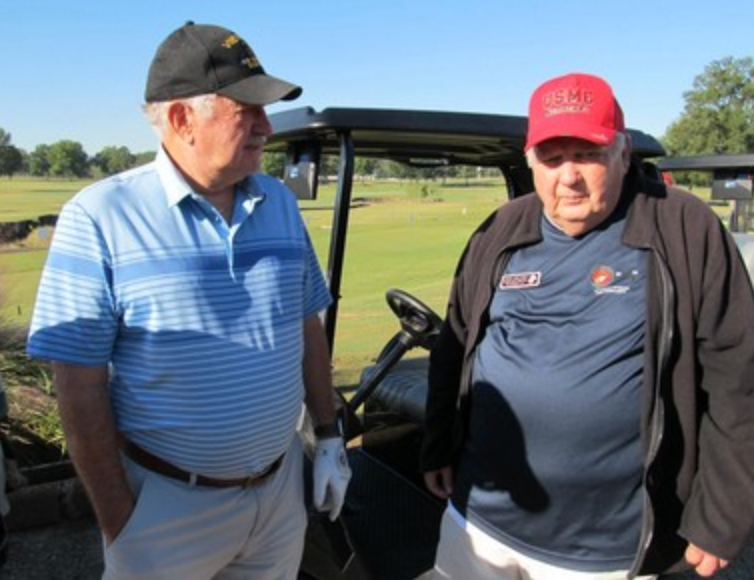 Two Marines chatting beside a golf cart on the course
