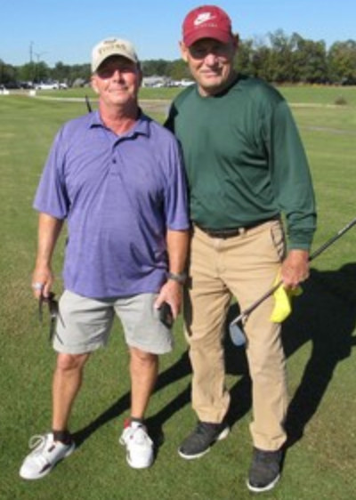 Two golfers posing together, one in purple and one in green
