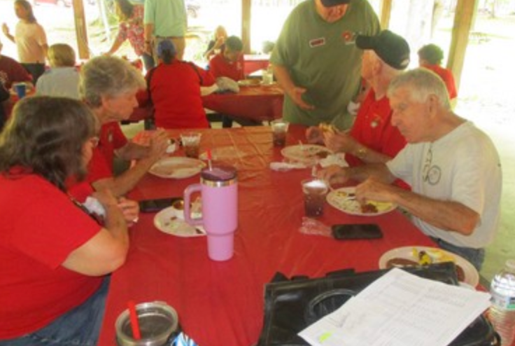 Members eating at table in pavilion