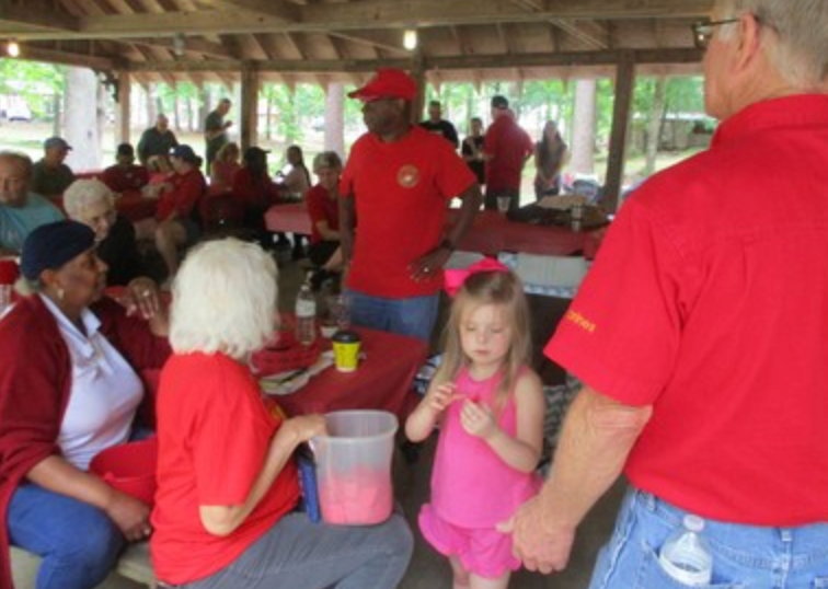 Large group gathering in pavilion with child