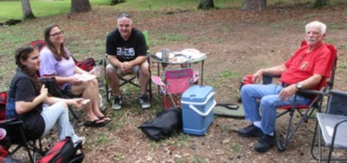 Four members seated in lawn chairs outdoors
