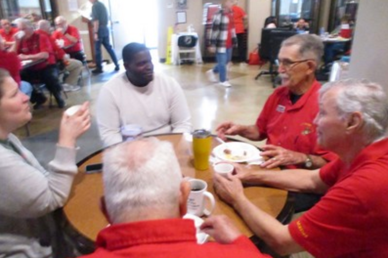 Group of members seated at round table at indoor event