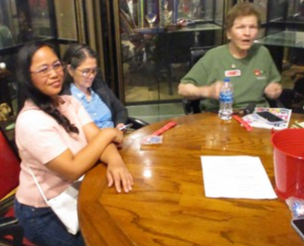 Three women seated at round table at indoor event