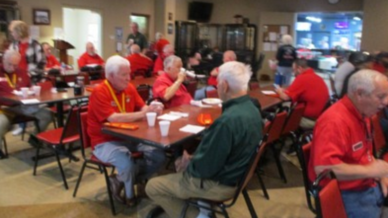 Large group of members in red shirts seated at tables