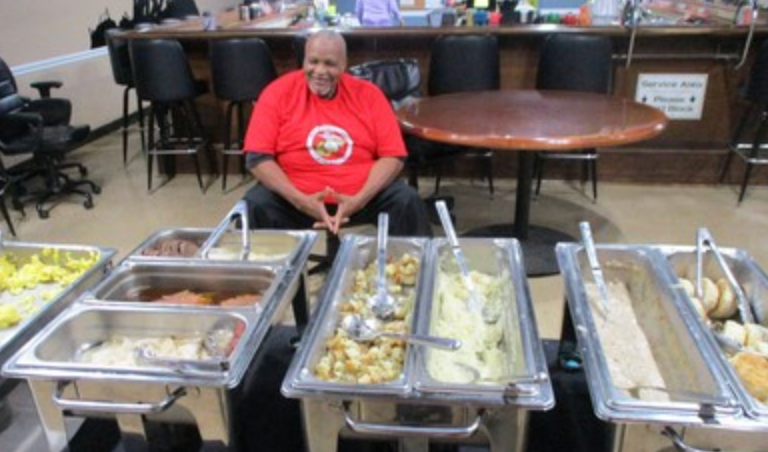 Member in red shirt seated behind buffet food trays