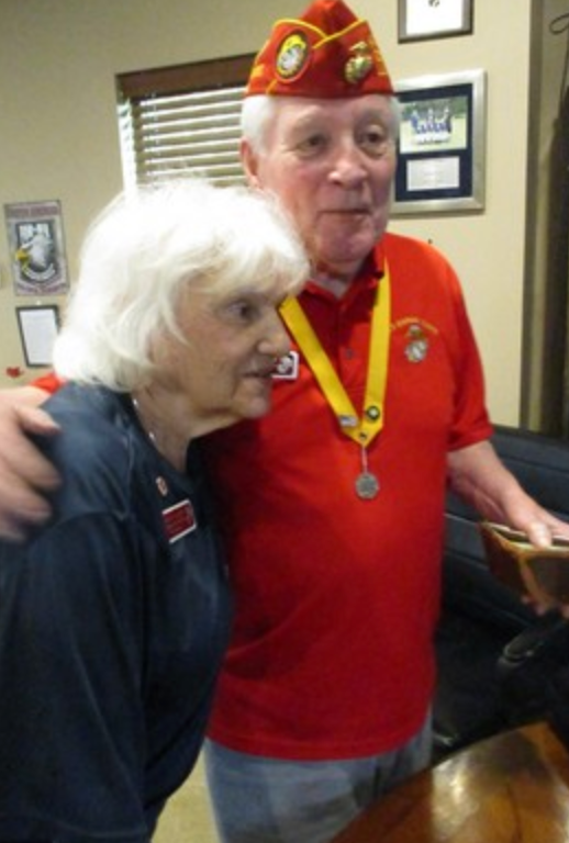 Member with medal and woman at indoor event