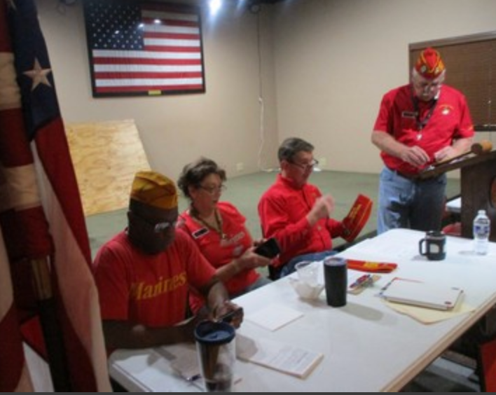 Members in red shirts at meeting table with flags