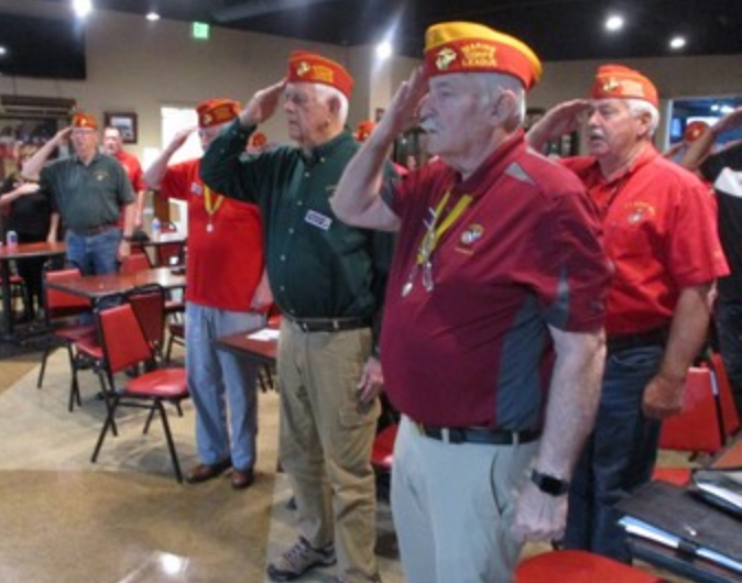 Members saluting at indoor meeting