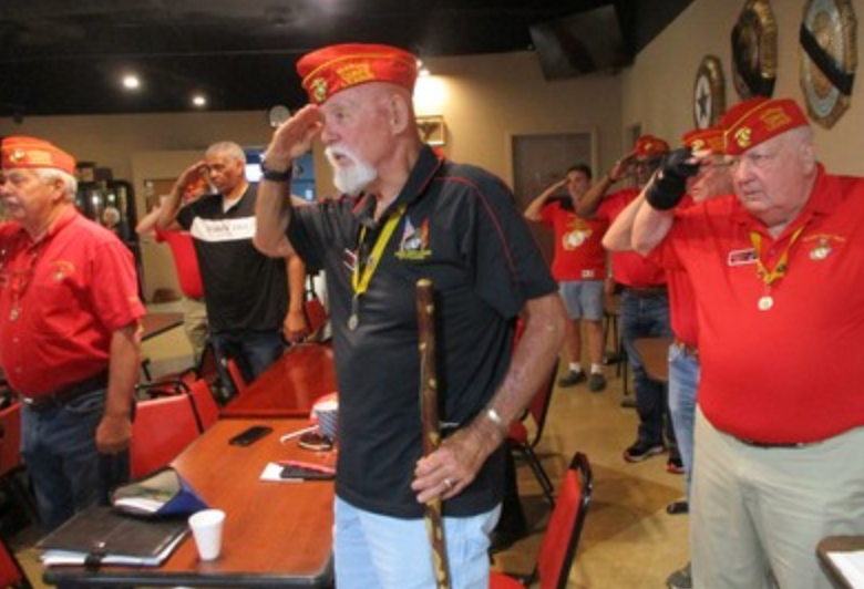 Members saluting at indoor meeting with cane