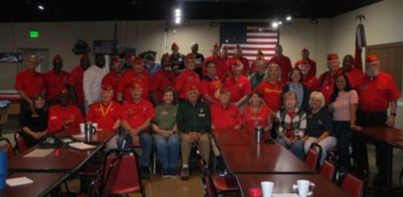 Large group photo of members in red shirts at indoor event