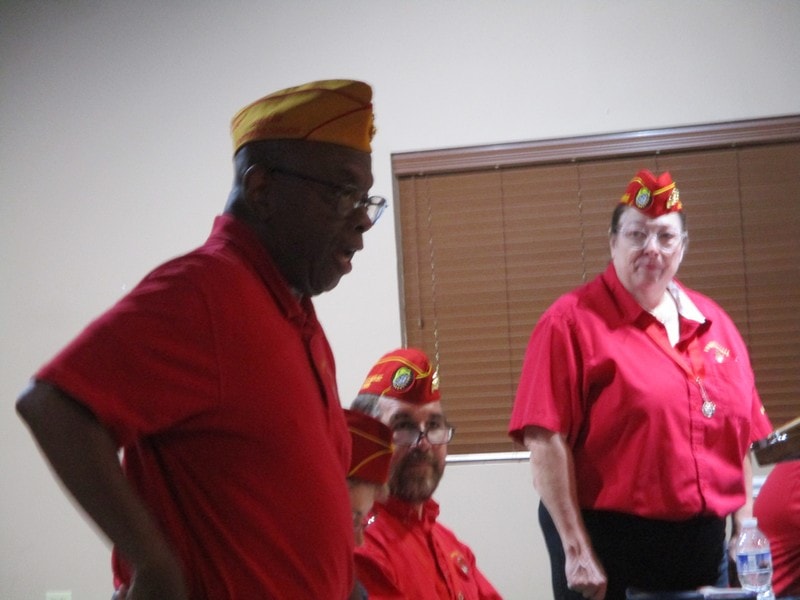 Veterans in red uniforms wearing ceremonial hats