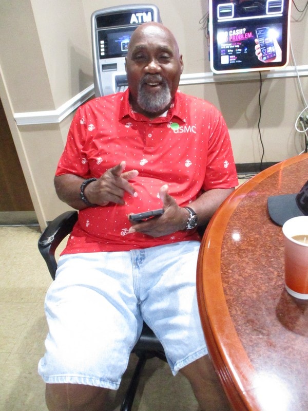 Member in red shirt sitting indoors talking