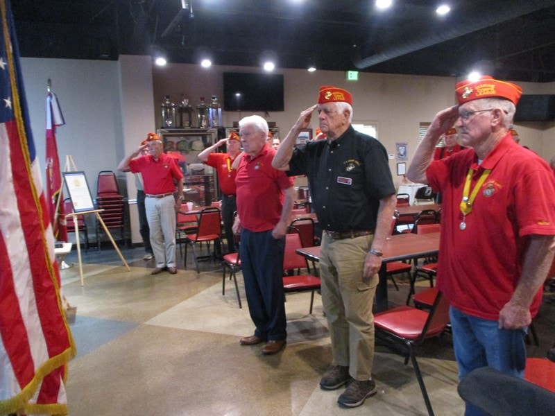 Military veterans saluting indoors at ceremony