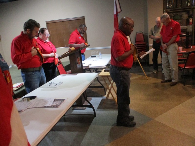 Group in red shirts holding tools indoors