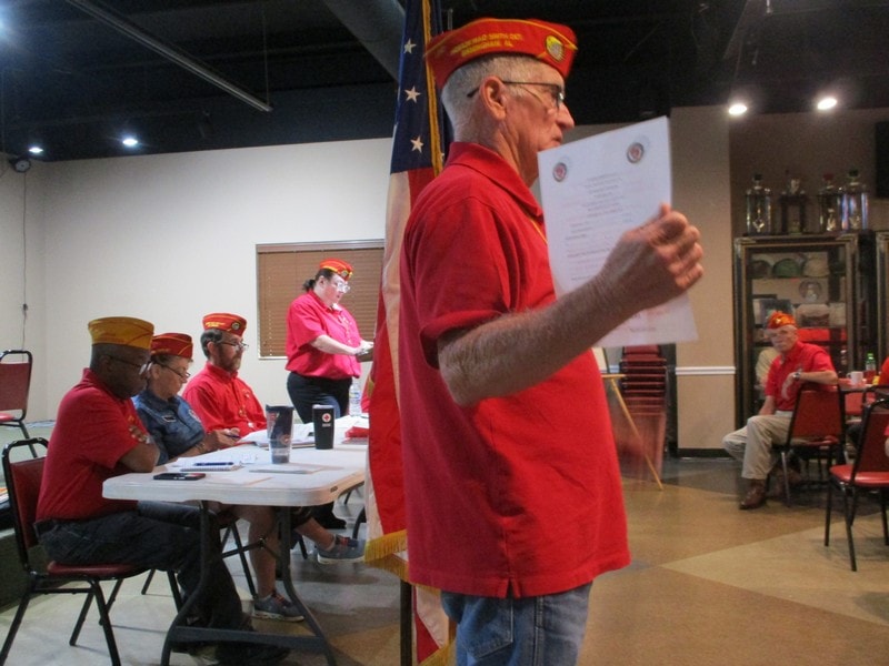 Veteran in red addressing military organization meeting