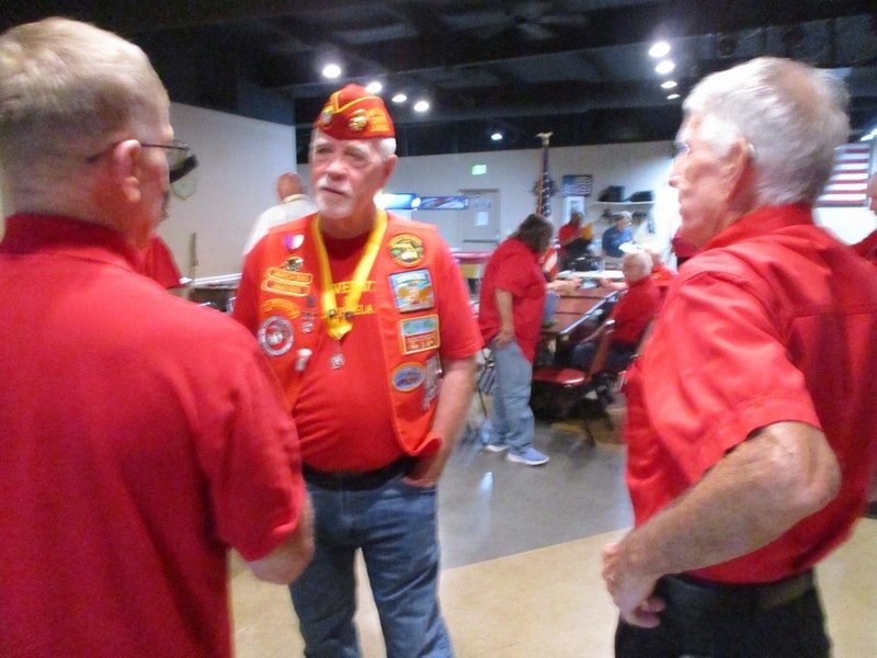 Veterans in red uniforms conversing indoors