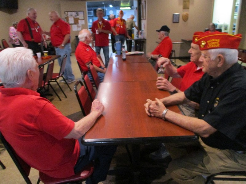 Veterans gathering indoors wearing red shirts