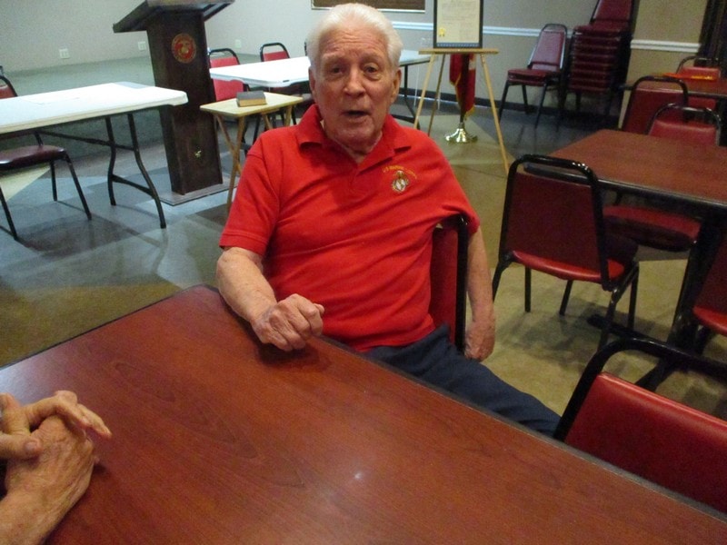 Elderly member in red shirt at table