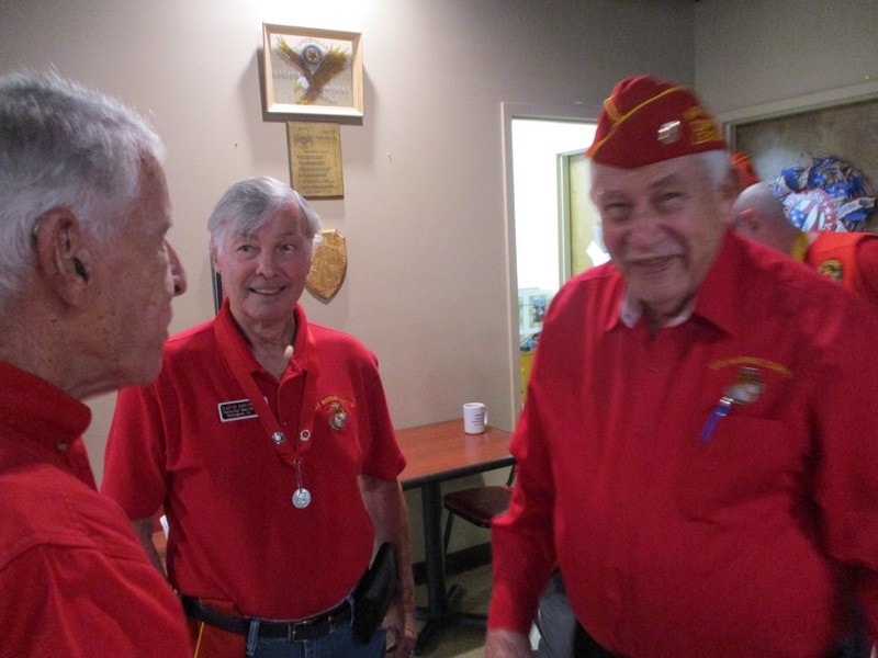 Senior veterans in red uniforms conversing indoors
