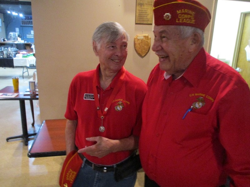 Two Marine veterans in red uniforms smiling