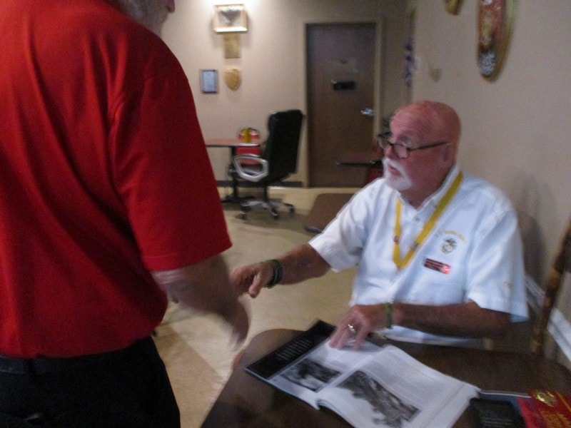 Member in white shirt greeting visitor indoors