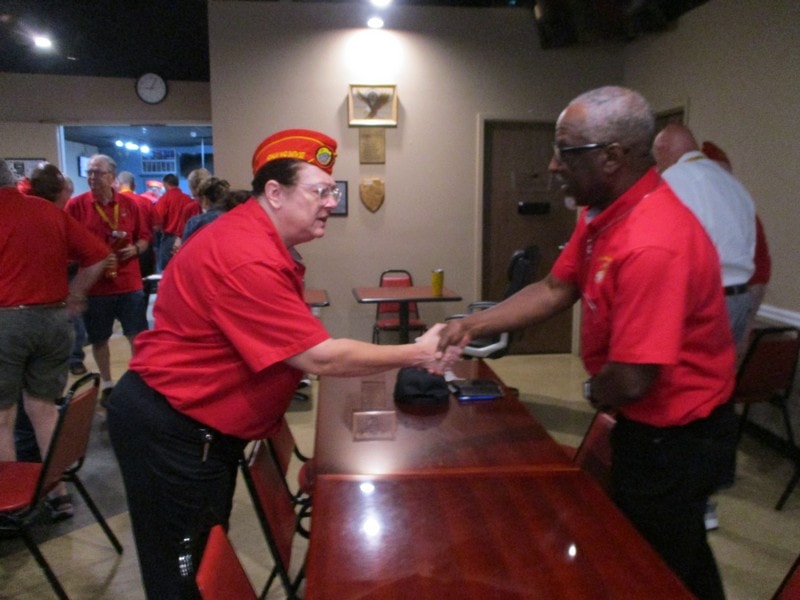 Members in red shirts shaking hands indoors