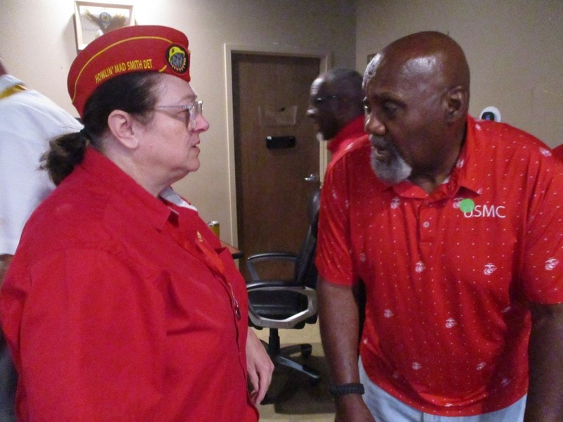 Two members in red uniforms conversing indoors