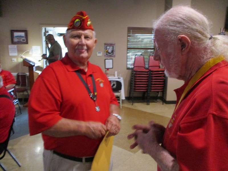 Veterans in red uniforms conversing indoors