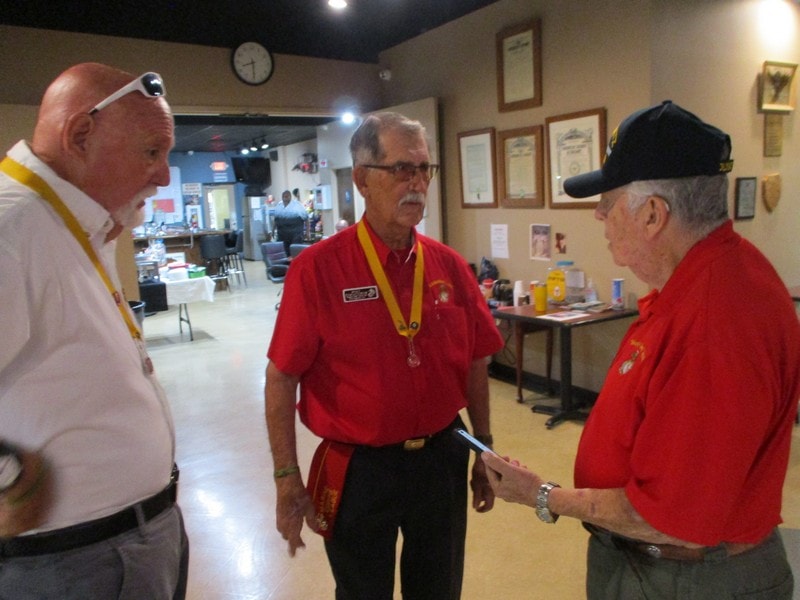 Three members conversing indoors wearing lanyards