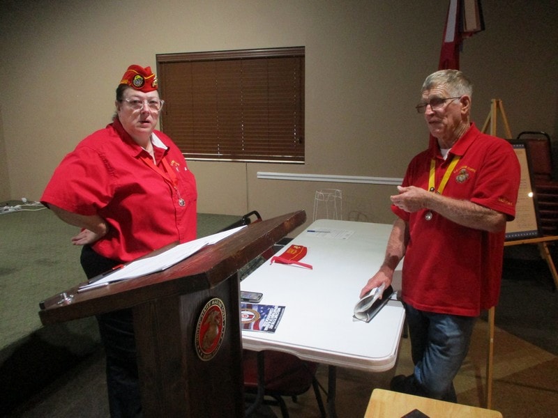 Two veterans in red uniforms discussing wooden model